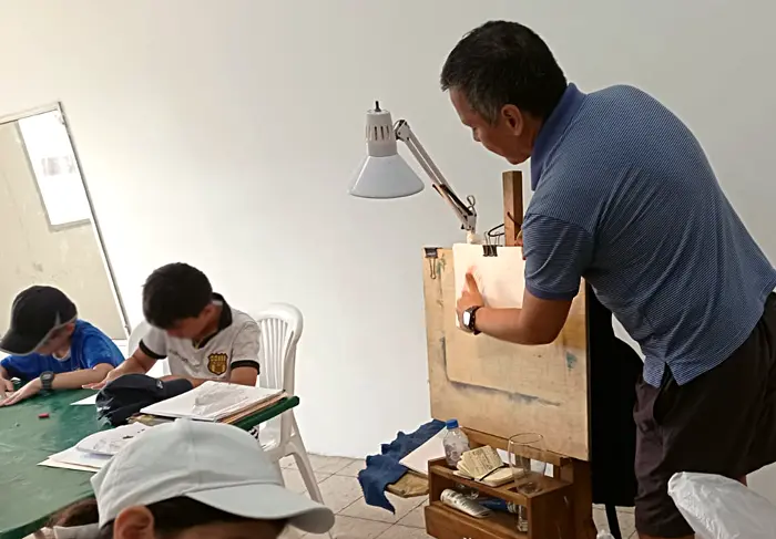Escena de niños e instructor frente a caballete de pintura, durante taller de arte en vacacional del Comité Los Ceibos, Guayaquil, Ecuador, www.duduromeroa.com